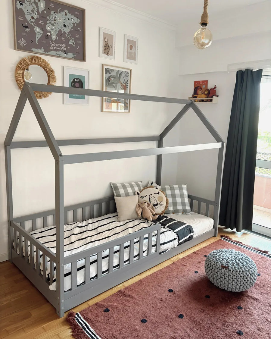 Children's room with a gray house-shaped bed, cushions, and a world map on the wall.