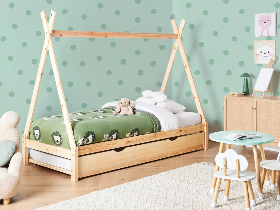 Children's room with a wooden teepee bed, green wall with polka dots, and small furniture.