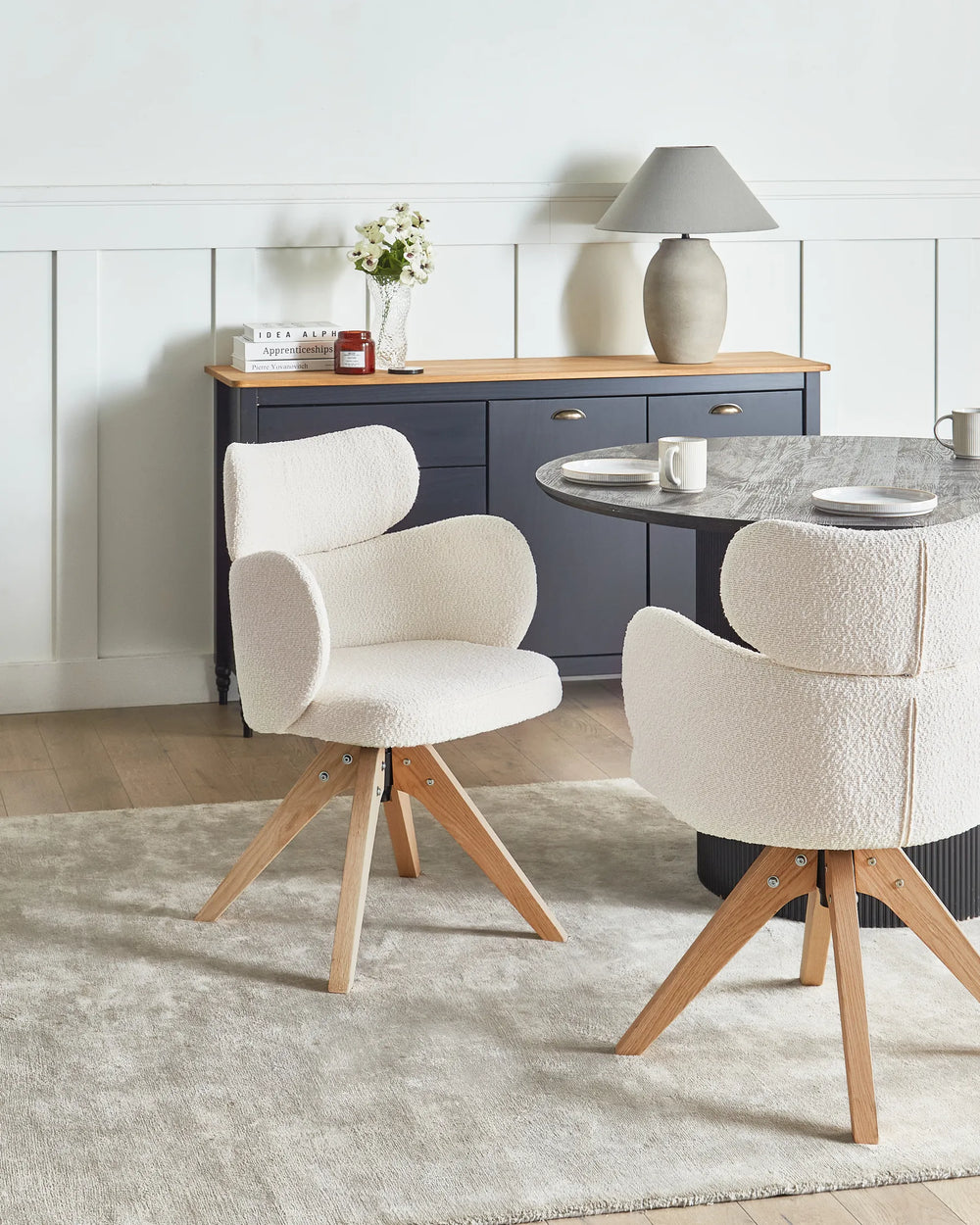 Elegant cream bouclé swivel chairs styled around a contemporary dining table, creating a warm and sophisticated dining setting.
