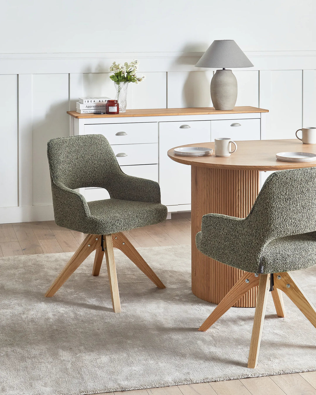 Modern grey bouclé swivel chairs styled around a wood dining table for a cozy, contemporary dining space.
