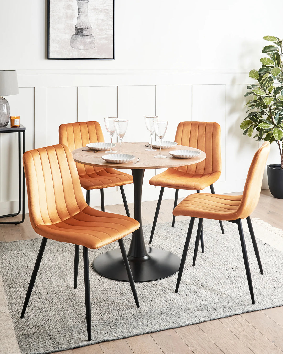 Contemporary dining set featuring warm mustard velvet chairs around a round table, adding a bold retro-modern accent to the space.