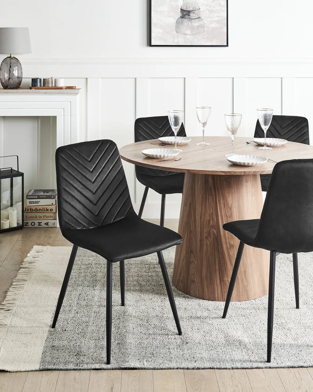 Black velvet dining chairs styled around a round wood dining table in a modern monochrome dining space.