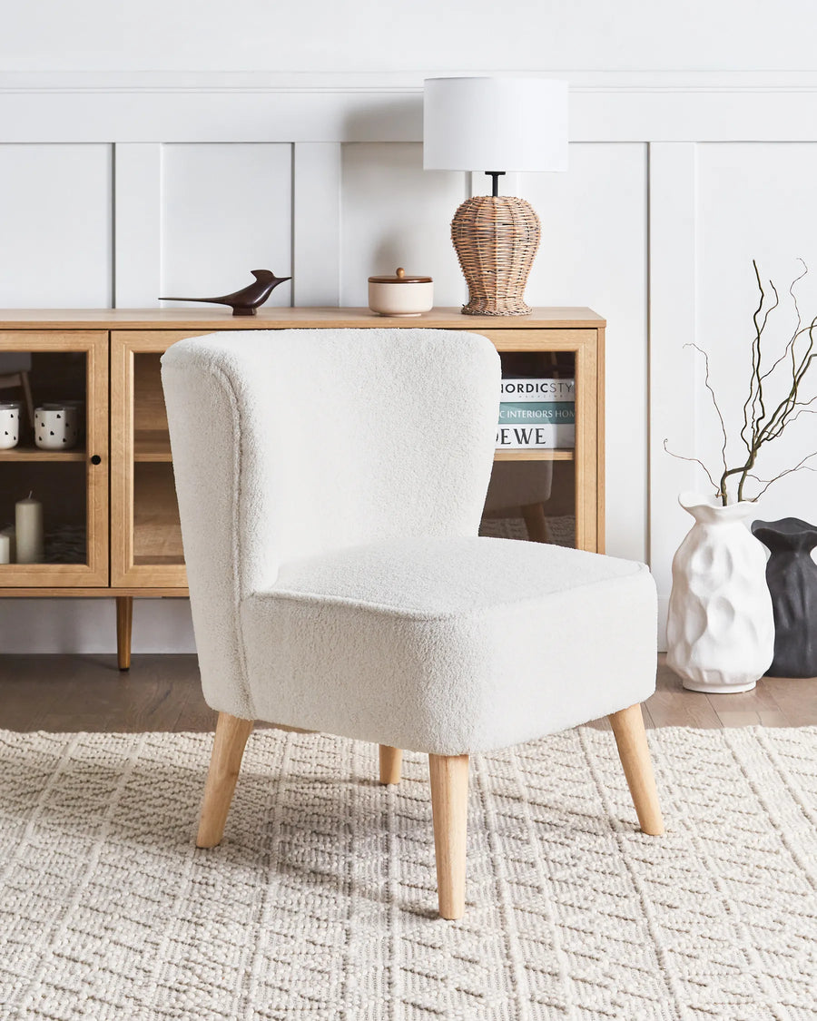 White armchair in a room with wooden cabinet and decorative items