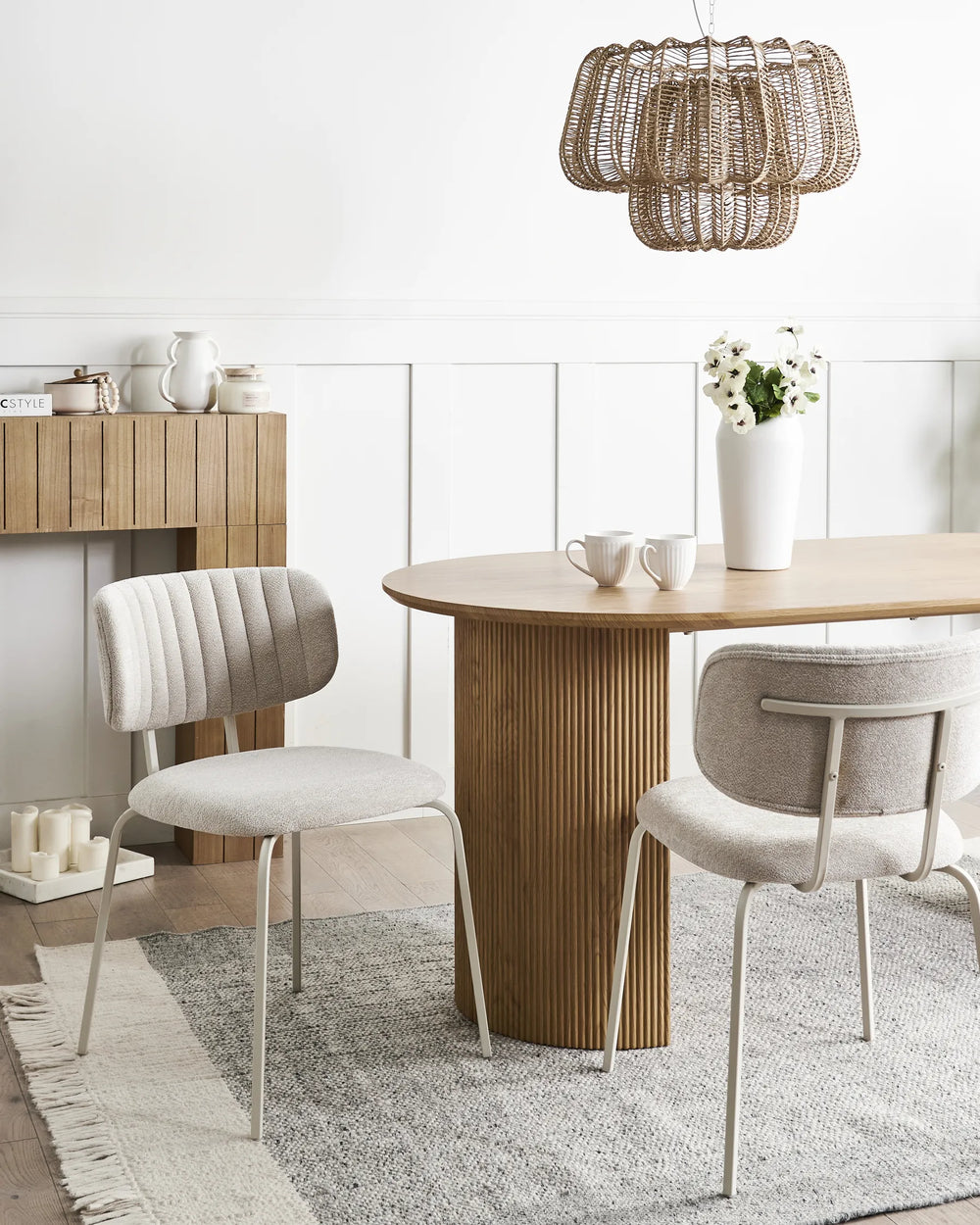 Light beige chenille dining chairs with stitched backrests and black metal legs arranged around a dining table in a bright, modern dining space with minimalist décor.