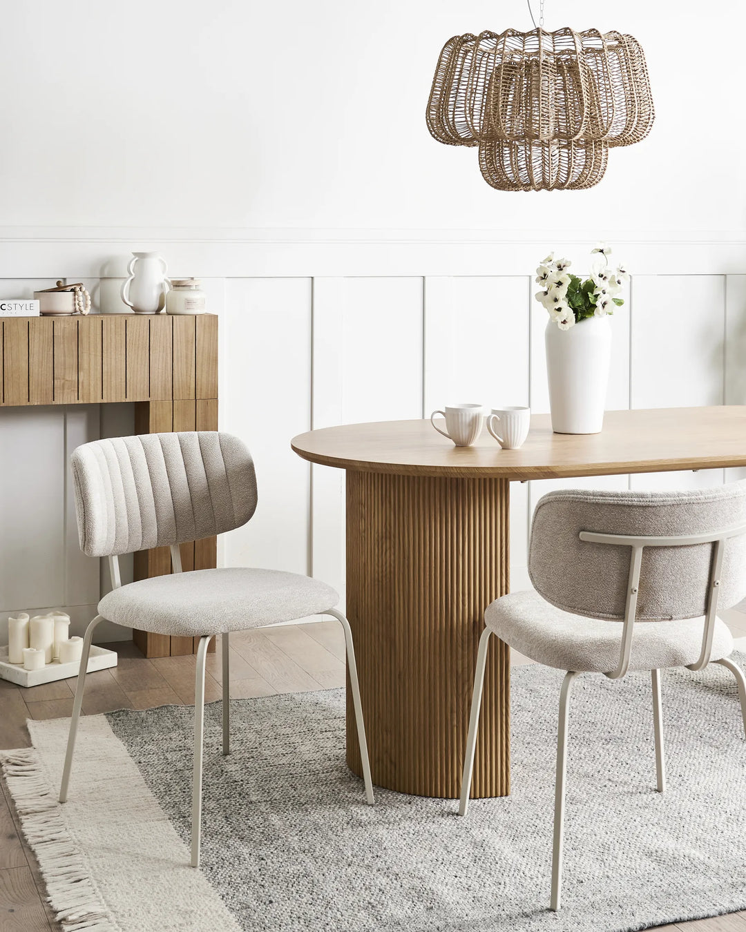 Light beige chenille dining chairs with stitched backrests and black metal legs arranged around a dining table in a bright, modern dining space with minimalist décor.