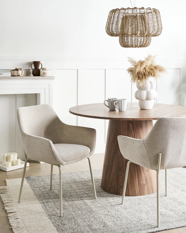 Beige boucle dining chairs around a round wood dining table.