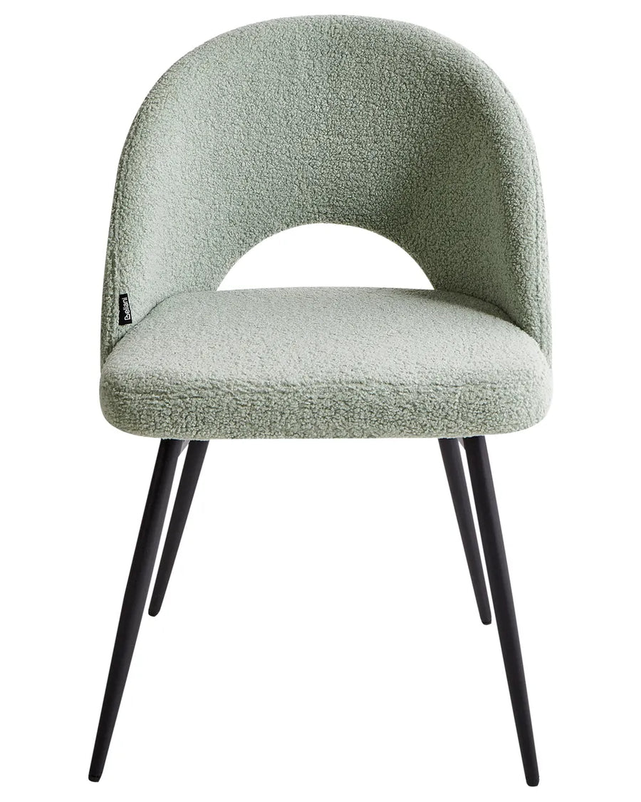 Sage green bouclé dining chair with a sculptural open-back design and black metal legs.