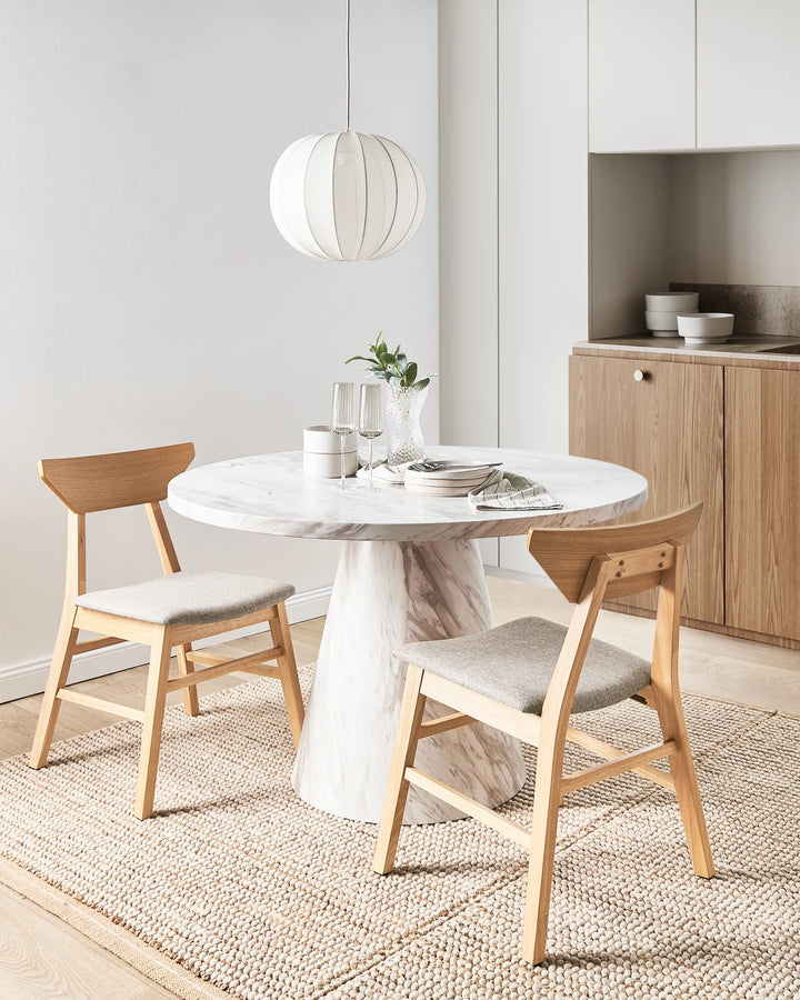 Styled around a sophisticated marble dining table, this wooden dining chair brings warmth and understated elegance to the space. The natural oak frame contrasts beautifully with the light-grey upholstered seat, creating a refined yet inviting atmosphere. Paired with soft neutral tones and modern décor, the chair enhances contemporary dining rooms with its balance of comfort, functionality, and Scandinavian-inspired design.