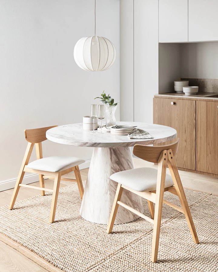 Styled around a contemporary marble dining table, this upholstered chair enhances the space with its warm natural wood tones and soft neutral palette. The sleek profile blends effortlessly with Scandinavian, Japandi, and modern interiors, offering a refined balance of comfort, functionality, and timeless design for casual meals or elegant gatherings.