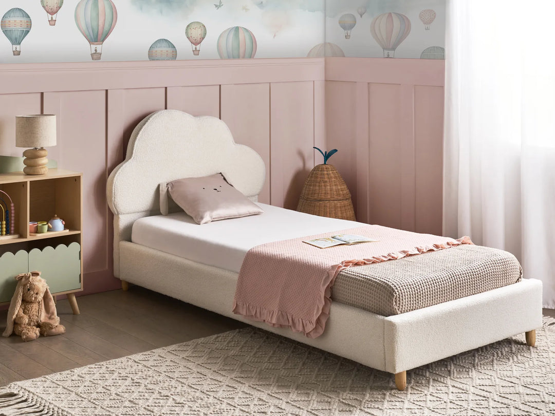 Children's bedroom with a white bed, pink headboard, and colorful hot air balloon wallpaper.