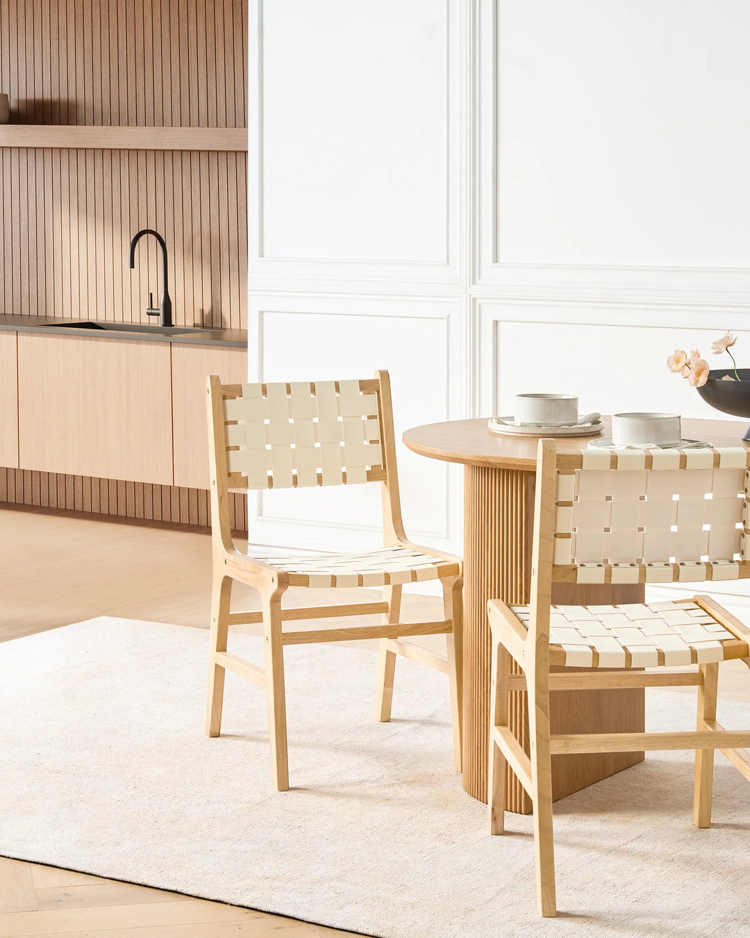 Styled around a modern round dining table, these woven dining chairs bring a warm Scandinavian aesthetic, blending natural textures and clean lines to create a bright and inviting dining space.