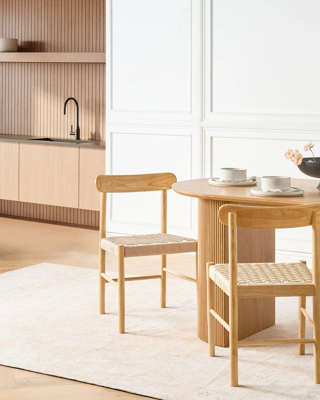 Light wood woven dining chairs styled in a bright, modern dining space with soft neutrals and natural finishes, creating a calm, airy, and cozy atmosphere.