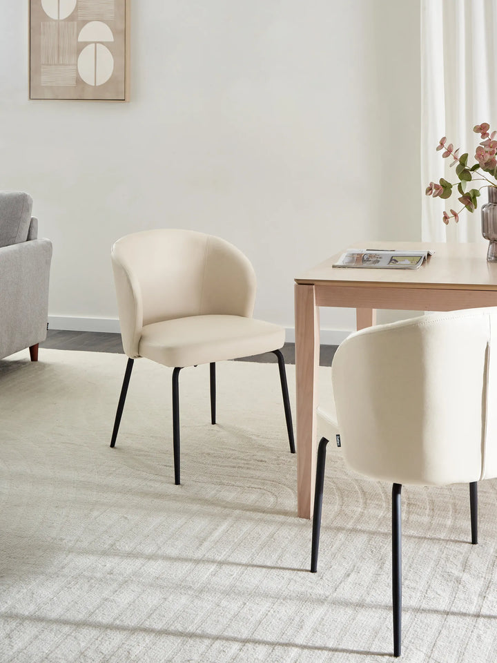 Modern dining space featuring the chair’s soft beige upholstery and sleek black frame, creating a warm, minimalist atmosphere ideal for contemporary interiors.