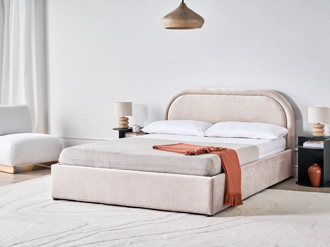 Beige upholstered bed with white bedding and a red blanket in a modern bedroom setting.