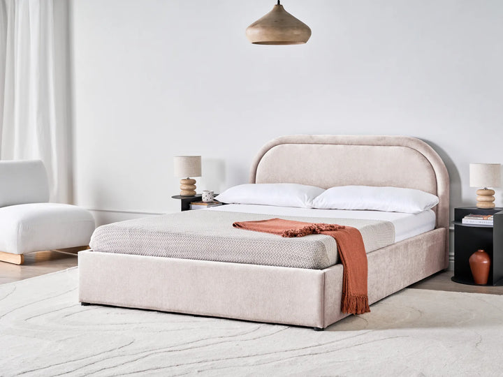 Beige upholstered bed with white bedding and a red blanket in a modern bedroom setting.