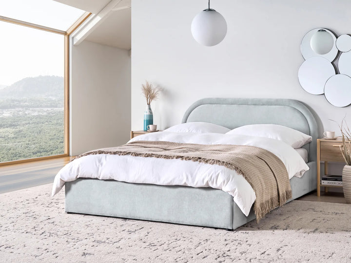 Modern bedroom with a gray upholstered bed and large windows.
