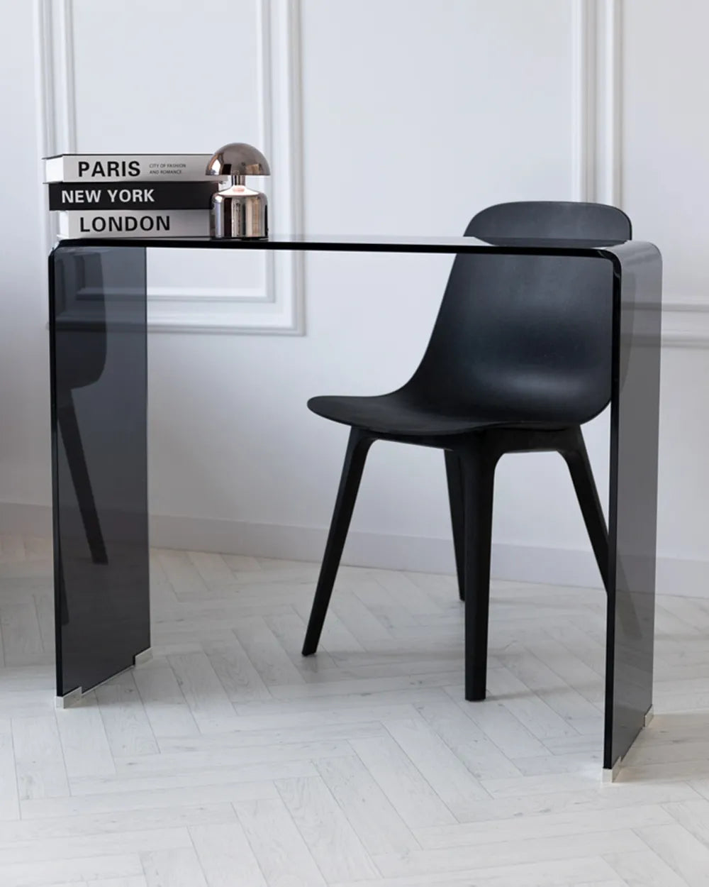 Black chair and table set against a white wall with books on the table.