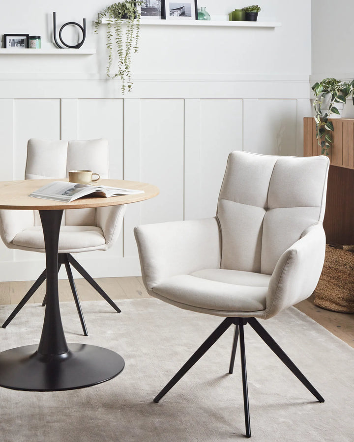 Cream swivel dining chairs styled around a round dining table in a bright modern dining room.