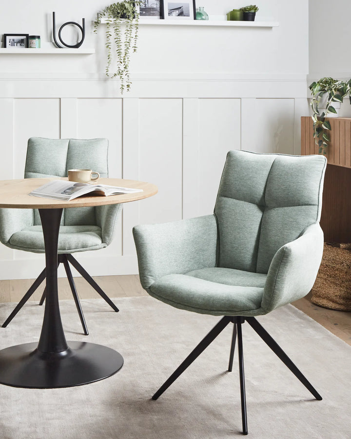 Sage green swivel dining chairs styled around a round dining table in a bright modern dining room.
