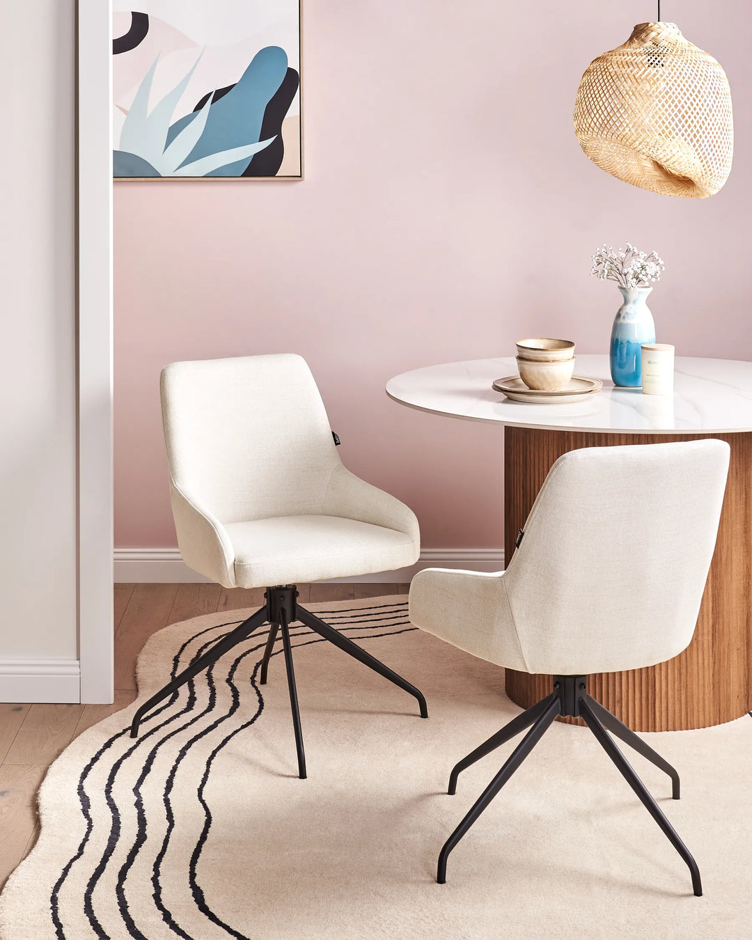 Off-white fabric swivel dining chairs with black metal bases around a dining table in a bright, modern dining space with minimalist décor.