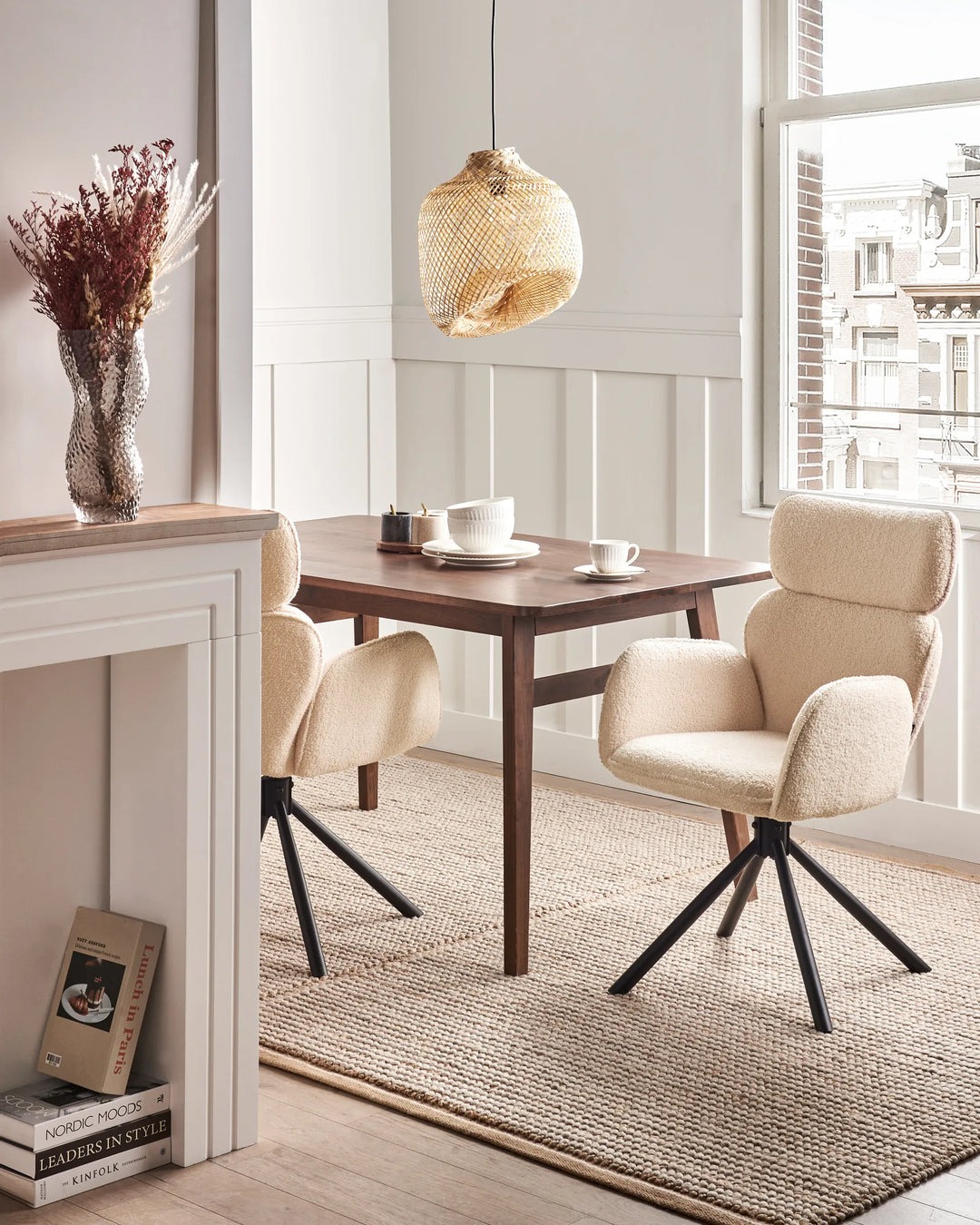 Cream bouclé swivel dining chairs styled around a wooden dining table in a bright, modern dining room.