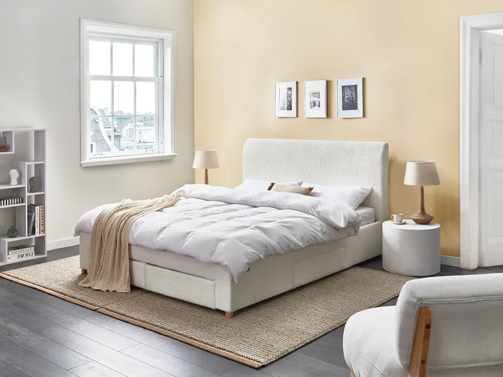 Modern bedroom with a white bed, beige rug, and light yellow walls.