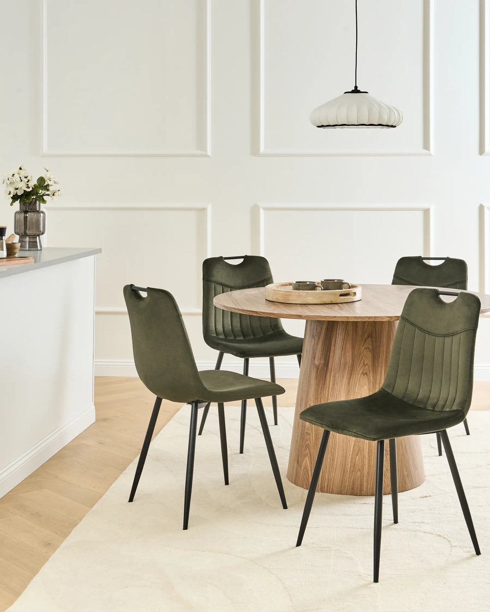 Dark green velvet dining chairs with tufted backrests and black metal legs arranged around a dining table in a modern dining space with contemporary décor.