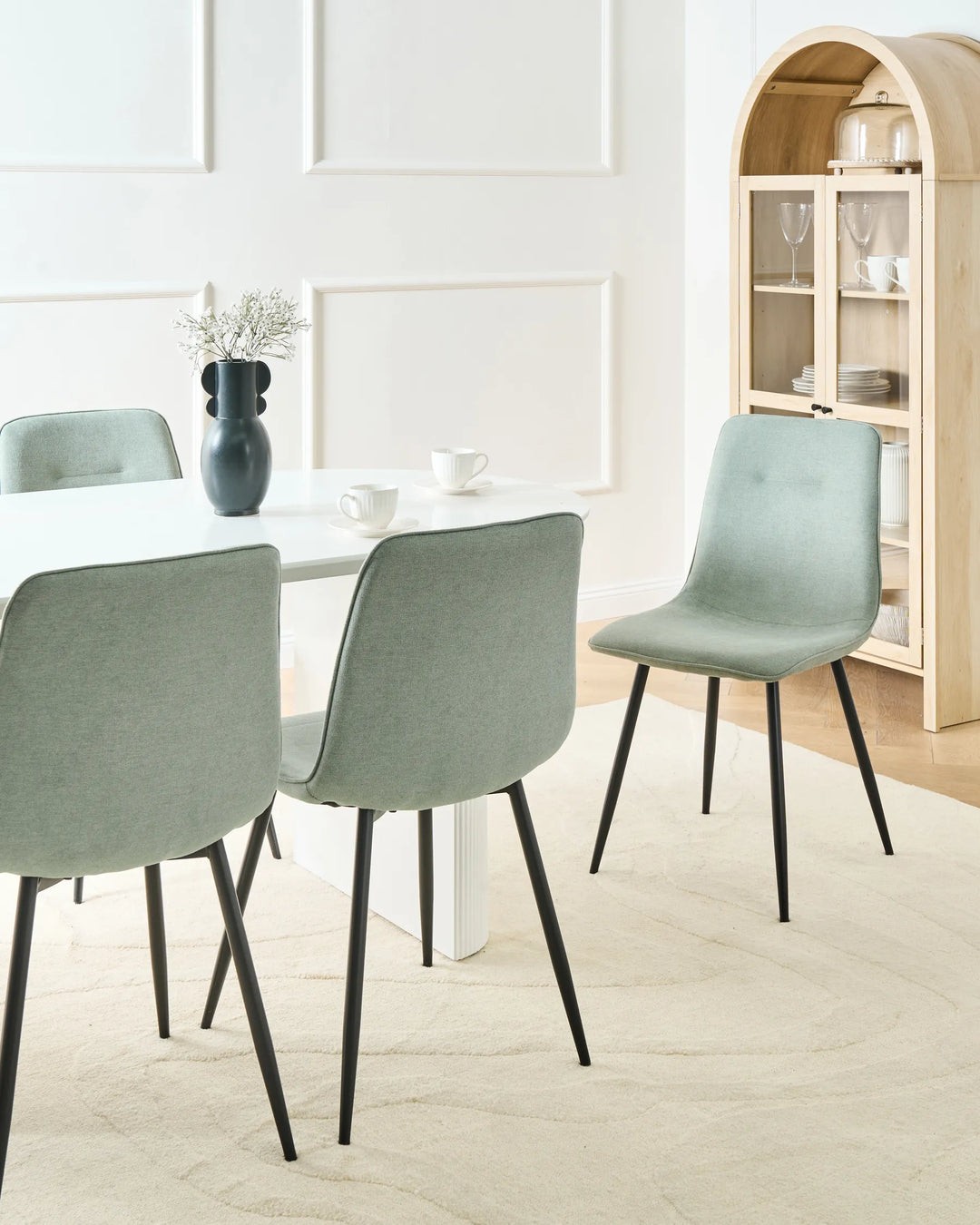 Modern light green dining chairs arranged around a white dining table, creating a fresh, airy, and contemporary dining space.