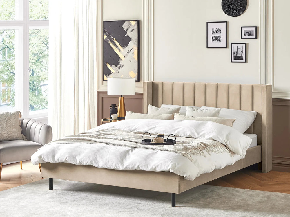 Beige upholstered bed in a bedroom with white bedding and decor.