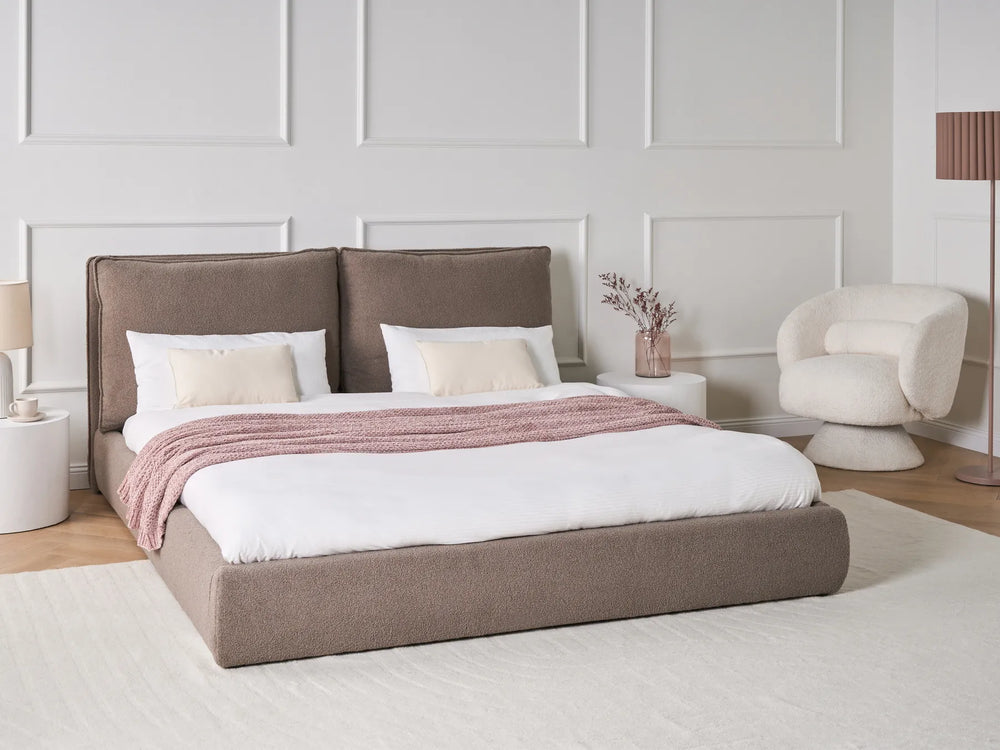 Modern bedroom with a brown upholstered bed and white walls.