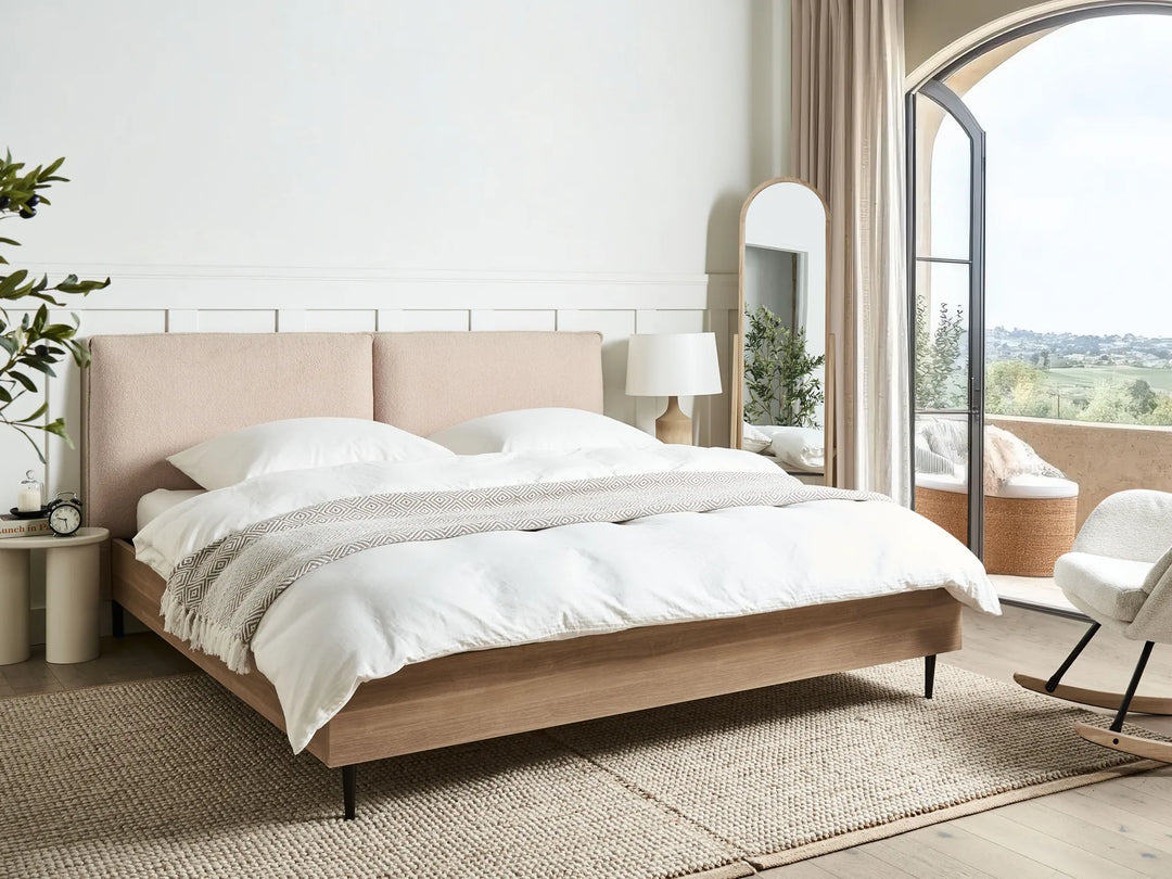 Modern bedroom with a bed, nightstands, and a view of a cityscape.