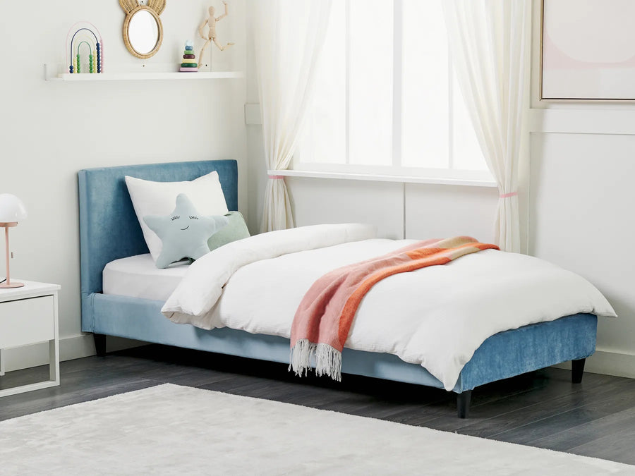 Blue upholstered bed with white bedding and a pink blanket in a bedroom setting.