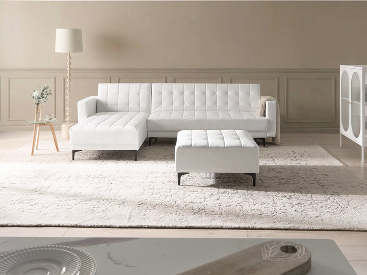 White sectional sofa with ottoman in a modern living room setting.