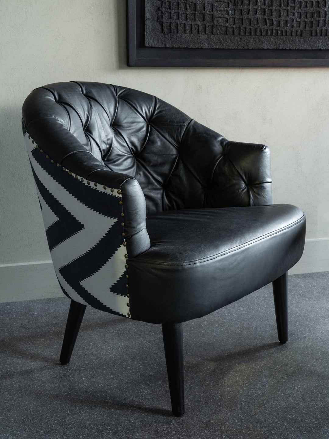 Black leather armchair with patterned backrest in a room setting