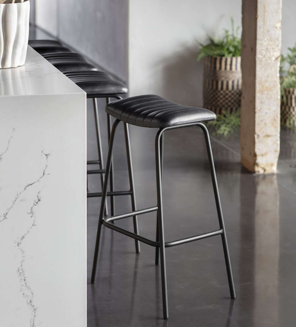 Bar stools with black seats and metal frames in a modern kitchen setting.
