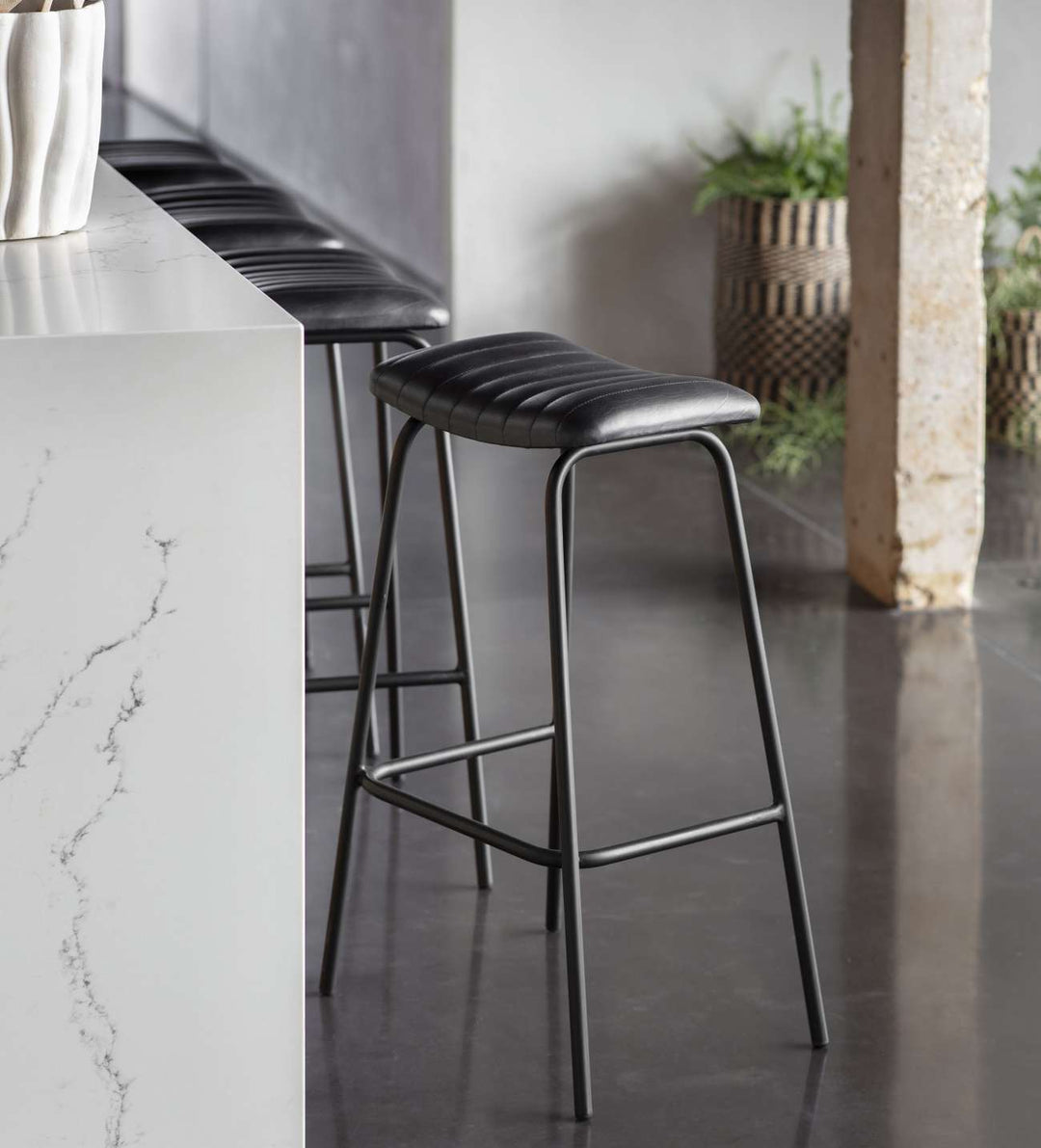 Bar stools with black seats and metal frames in a modern kitchen setting.