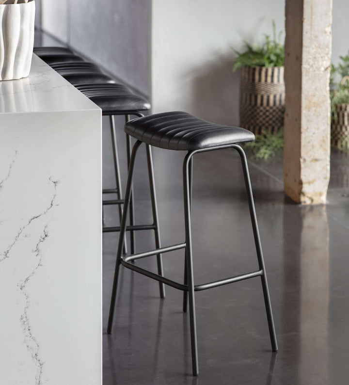 Bar stools with black seats and metal frames in a modern kitchen setting.