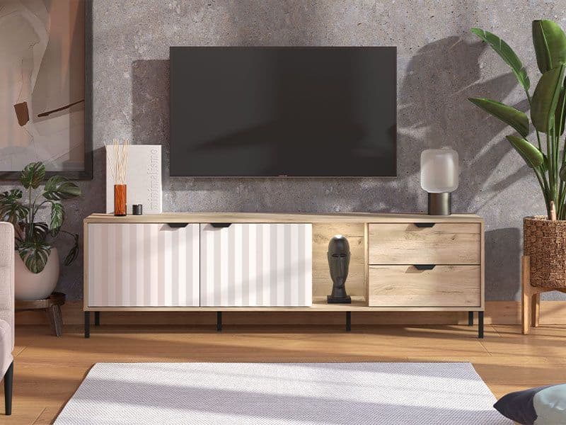 Wooden TV stand with a television mounted on a gray wall, surrounded by decorative items and plants.