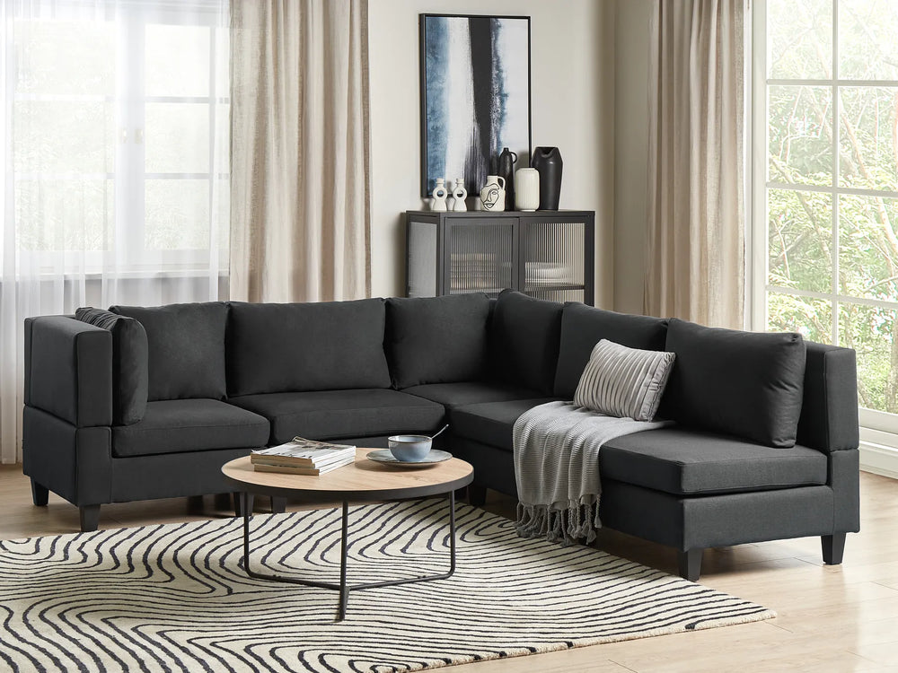 Modern living room with a black sectional sofa, coffee table, and decorative items.