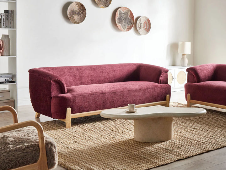 Modern living room with a red sofa and matching armchair, white coffee table, and decorative plates on the wall.