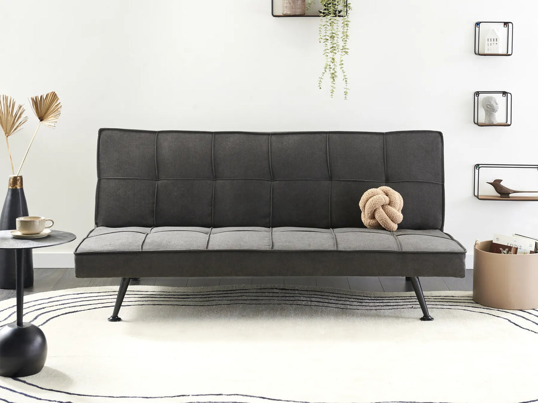 Black leather sofa bed in a modern living room setting with decor elements.