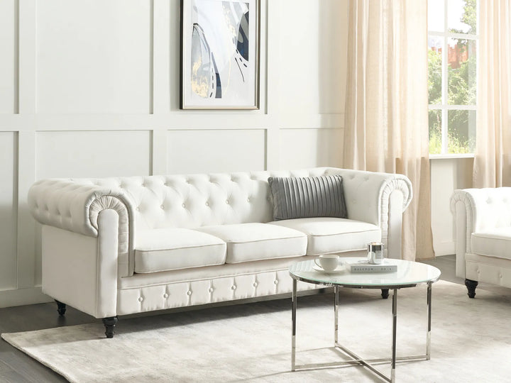 White tufted sofa in a living room with a coffee table and decorative items.