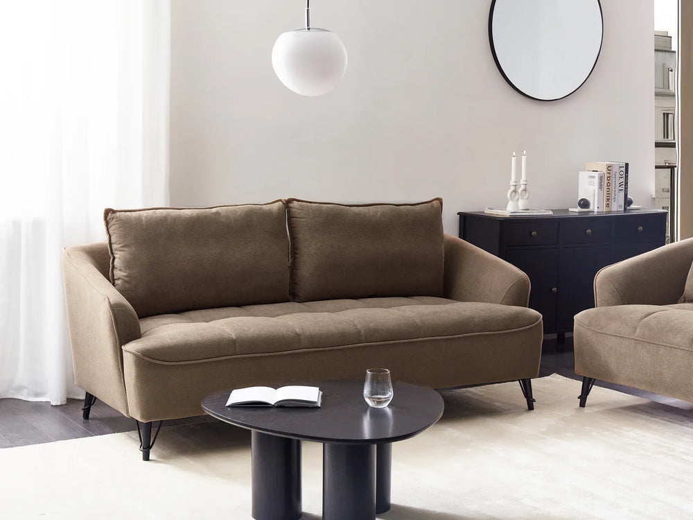 Brown sofa and armchair in a modern living room with a black coffee table and decorative items.