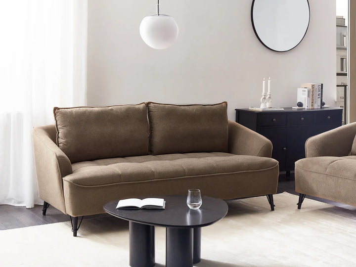 Brown sofa and armchair in a modern living room with a black coffee table and decorative items.