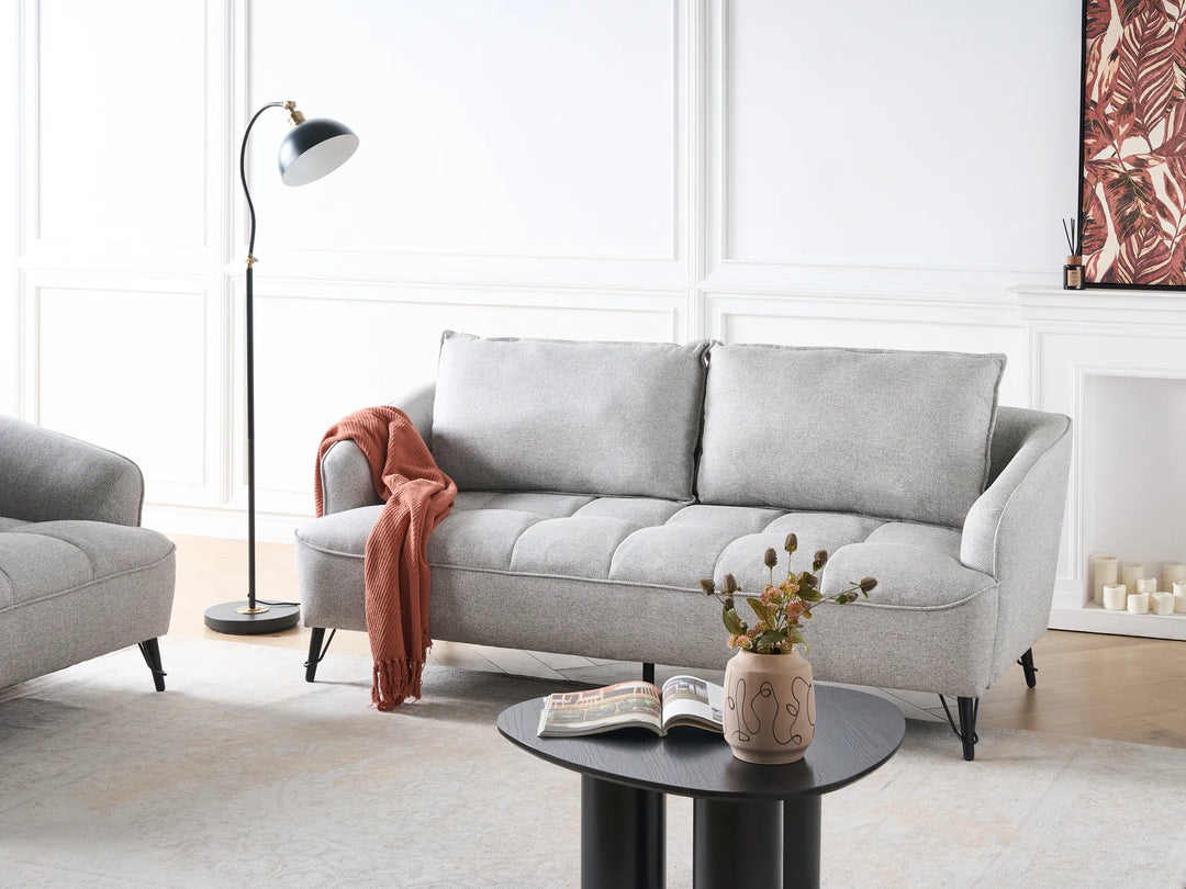 Gray sofa in a living room with a lamp, coffee table, and decorative items.