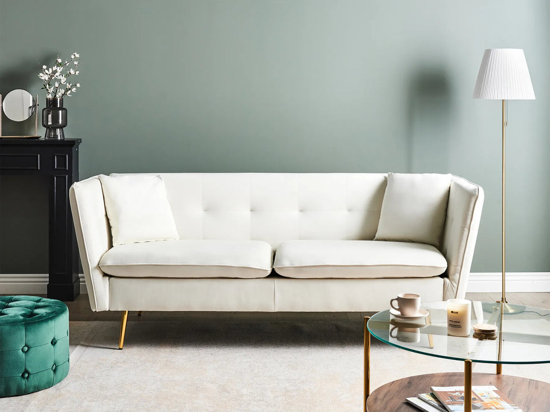 Modern living room with a white sofa, green ottoman, and decorative items.