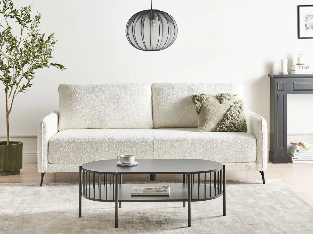 Modern living room with a white sofa, round metal coffee table, and decorative items.