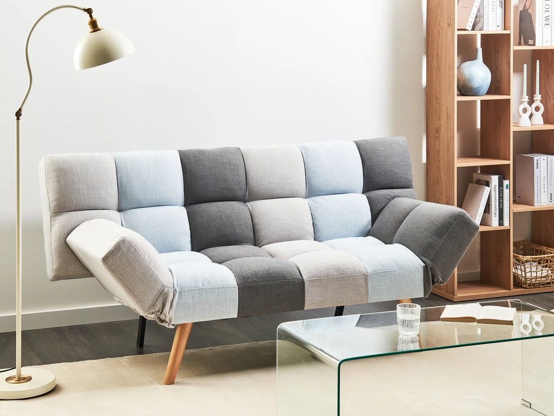 Gray and blue checkered sofa in a living room setting with a bookshelf and lamp.