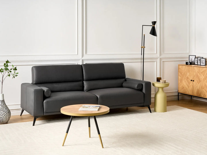 Modern living room with a black sofa, wooden coffee table, and side table.