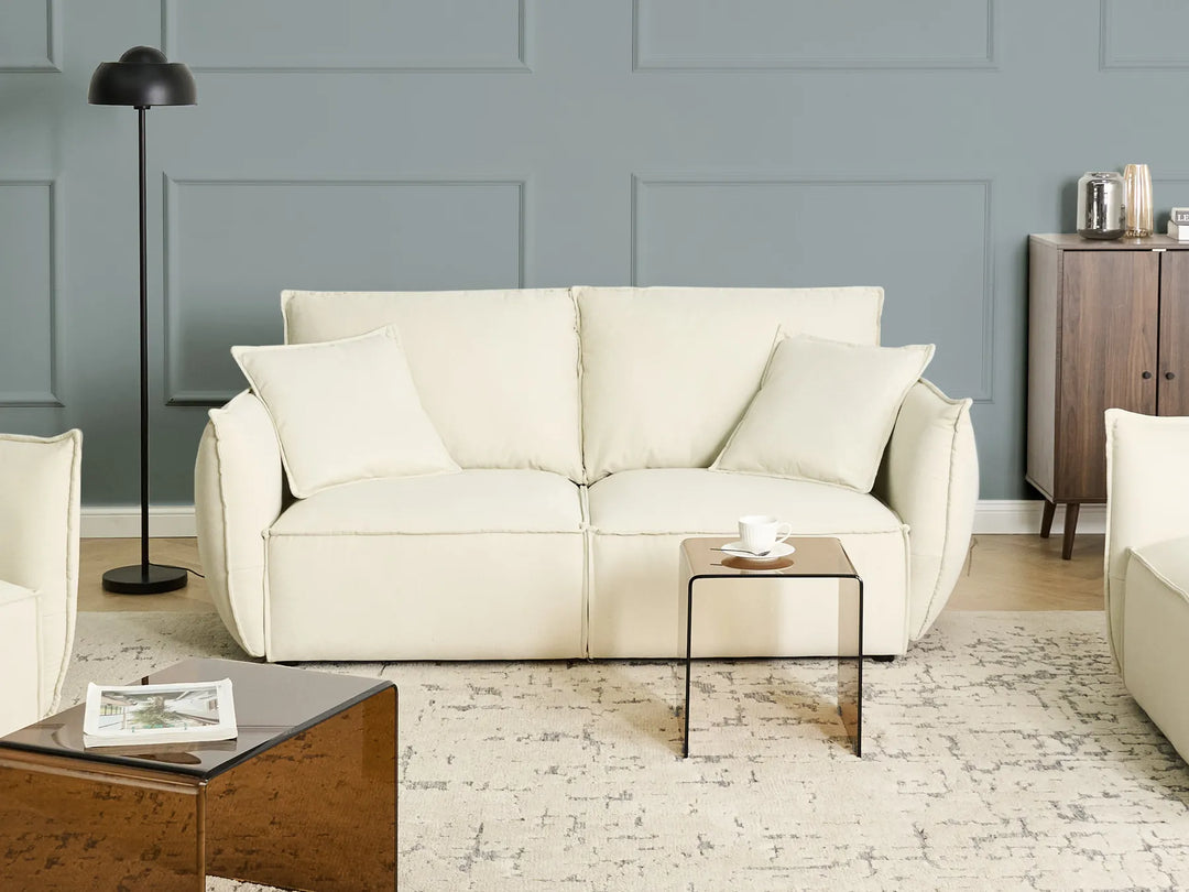 Beige sofa in a living room with a gray wall and wooden floor.